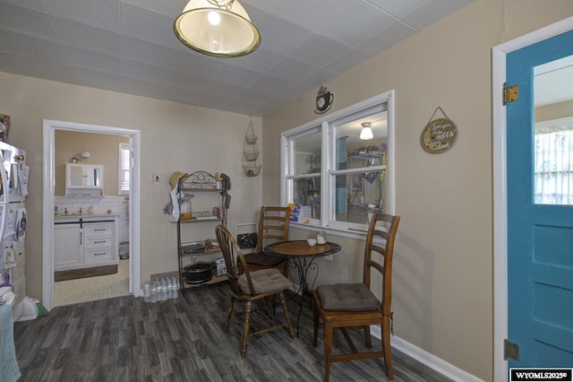 dining space featuring dark wood finished floors and baseboards