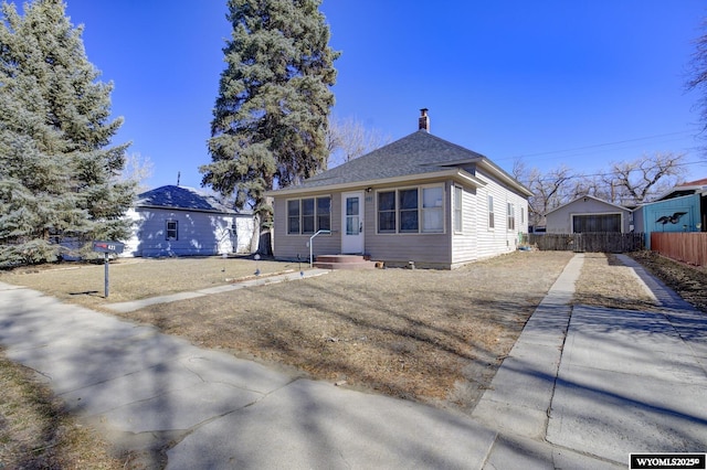 view of front of house with entry steps, a shingled roof, fence, and concrete driveway