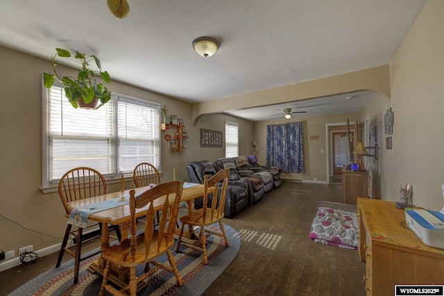 dining space featuring arched walkways, hardwood / wood-style flooring, and baseboards