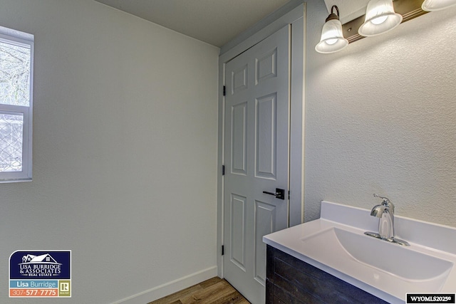 bathroom featuring wood finished floors, a sink, and baseboards