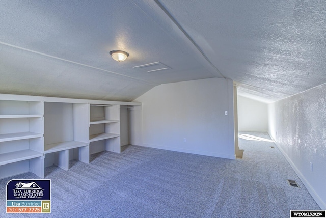 bonus room featuring a textured ceiling, baseboards, and light colored carpet