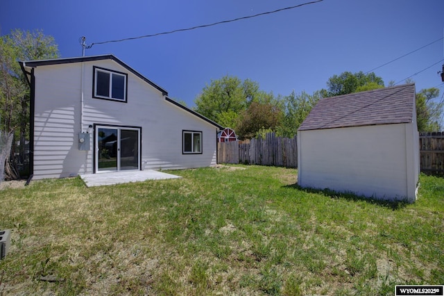 rear view of house featuring a storage shed, a fenced backyard, an outdoor structure, and a yard