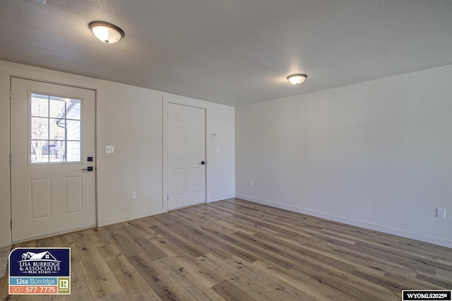 entryway featuring a textured ceiling, baseboards, and wood finished floors