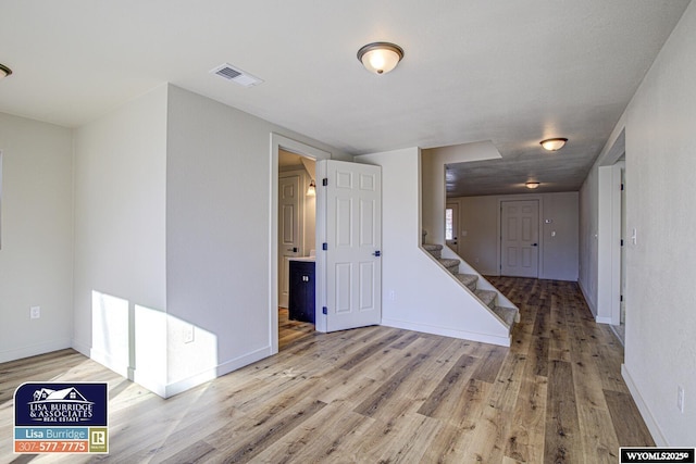 unfurnished room with baseboards, stairs, visible vents, and wood finished floors