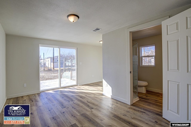 spare room featuring plenty of natural light, visible vents, and wood finished floors