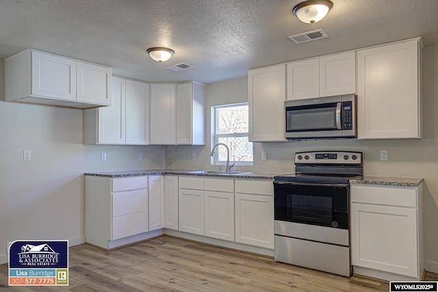 kitchen with light wood-style floors, visible vents, appliances with stainless steel finishes, and a sink