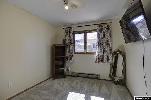 carpeted spare room featuring a baseboard heating unit and baseboards