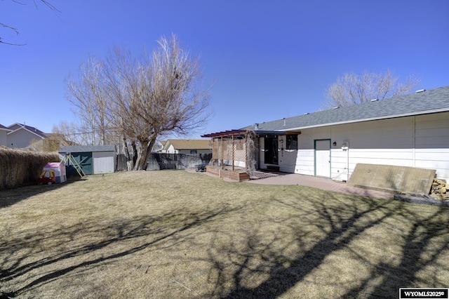 exterior space with a shingled roof, fence, a storage unit, an outdoor structure, and a patio area