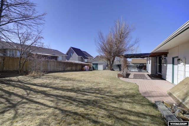 view of yard with a fenced backyard, a storage unit, a patio, and an outbuilding