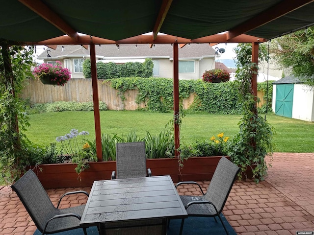 view of patio featuring a shed, outdoor dining space, an outdoor structure, and fence