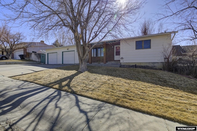 ranch-style home with an attached garage, fence, concrete driveway, and brick siding