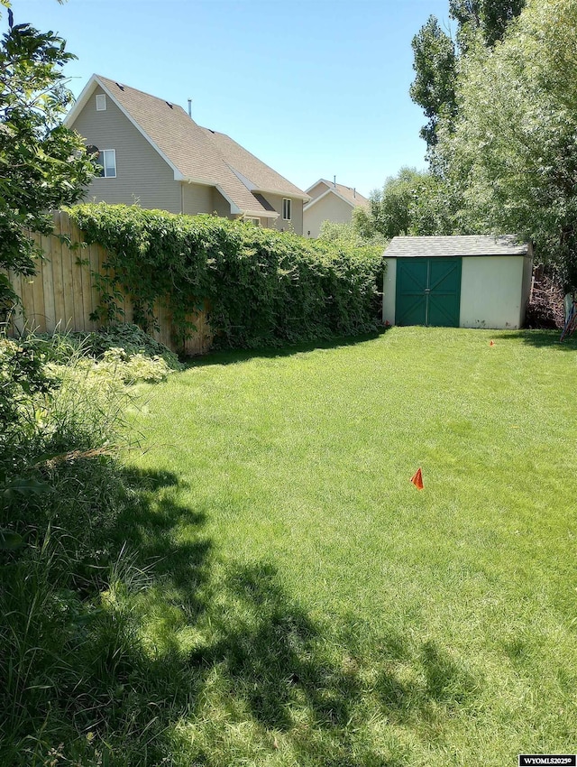 view of yard featuring an outbuilding, a shed, and fence