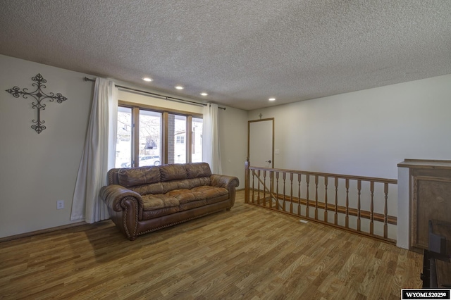 living area featuring recessed lighting, a textured ceiling, and wood finished floors