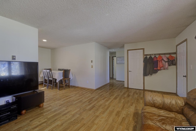 living area with baseboards, a textured ceiling, and light wood finished floors