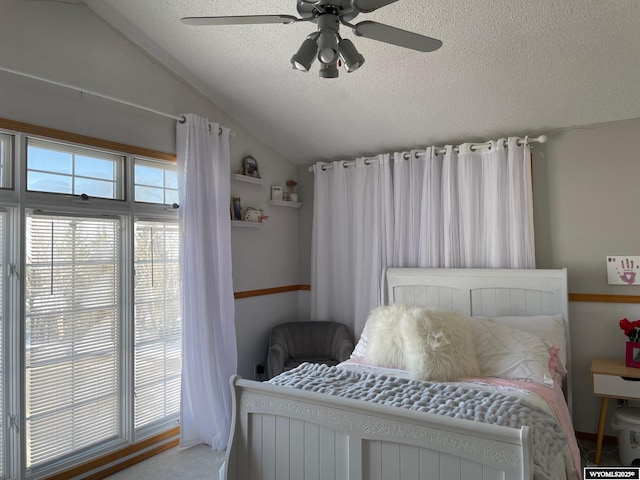 bedroom with a ceiling fan, multiple windows, vaulted ceiling, and a textured ceiling