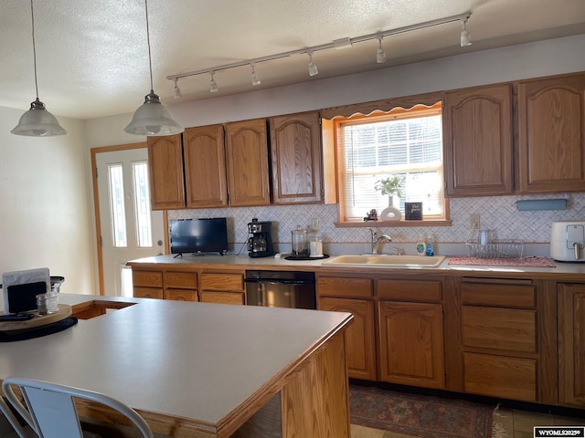 kitchen featuring a sink, tasteful backsplash, dishwasher, and decorative light fixtures