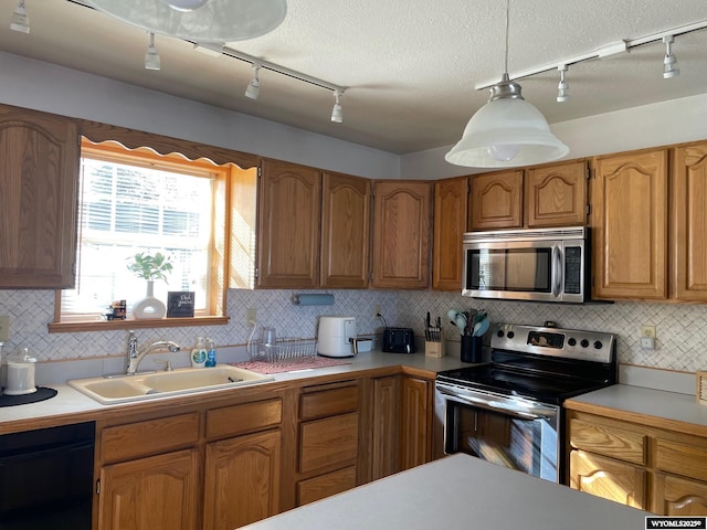 kitchen with brown cabinetry, stainless steel appliances, a sink, and light countertops