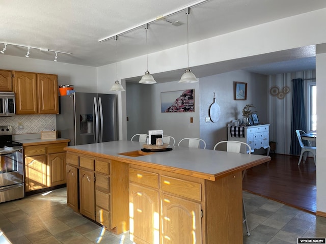 kitchen with appliances with stainless steel finishes, a kitchen breakfast bar, light countertops, and a center island