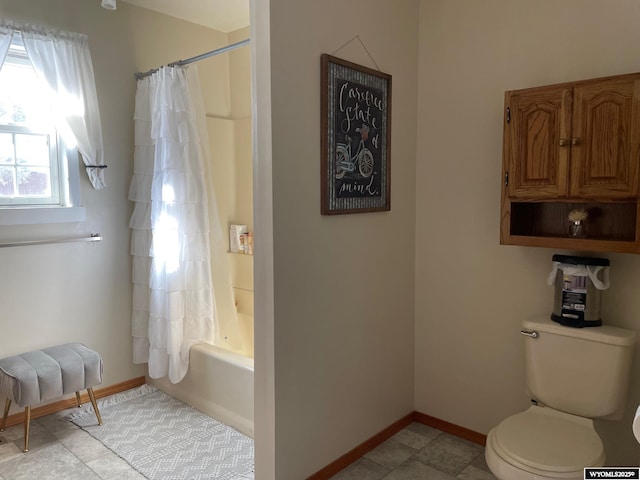 bathroom featuring shower / tub combo, toilet, and baseboards