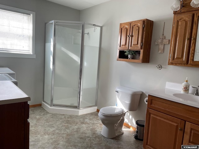 full bathroom with toilet, a stall shower, vanity, and baseboards