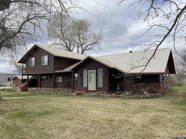 log home featuring stone siding, a front yard, faux log siding, and metal roof