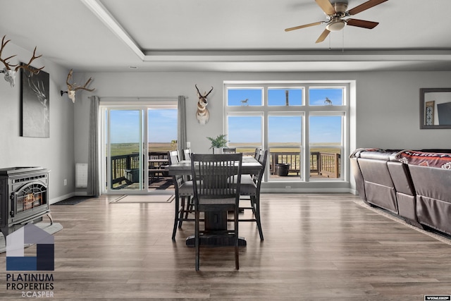 dining space featuring a wood stove, a healthy amount of sunlight, baseboards, and wood finished floors