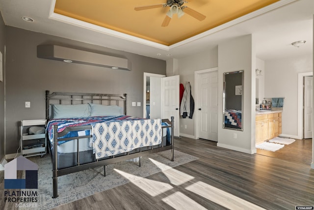 bedroom featuring baseboards, a tray ceiling, and wood finished floors