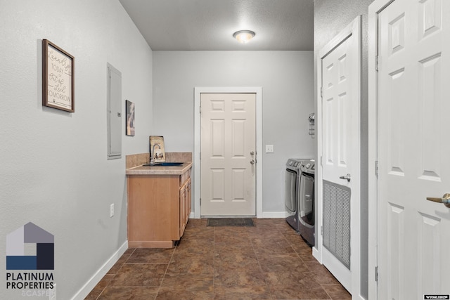 hallway featuring electric panel, baseboards, washer and clothes dryer, and a textured ceiling