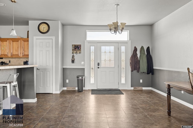 entrance foyer with baseboards and an inviting chandelier