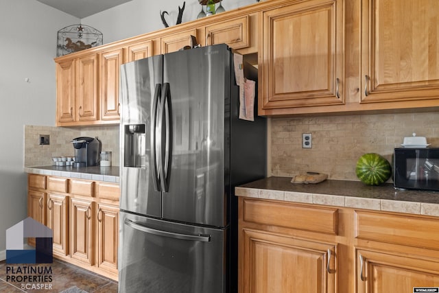 kitchen featuring tasteful backsplash, black microwave, and stainless steel fridge with ice dispenser