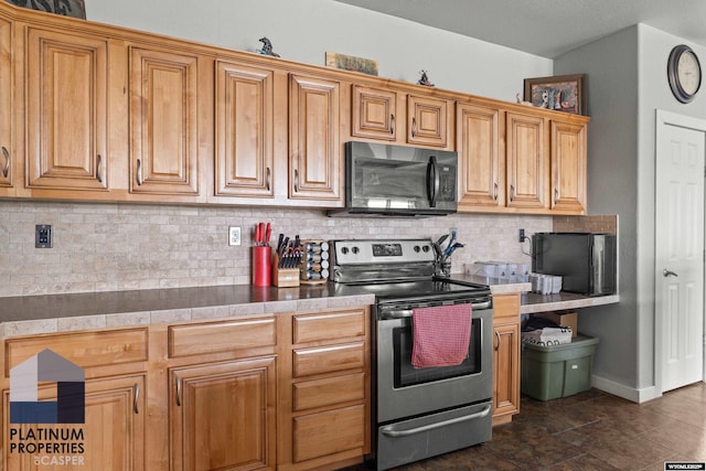 kitchen featuring black microwave, stainless steel electric stove, baseboards, decorative backsplash, and brown cabinets