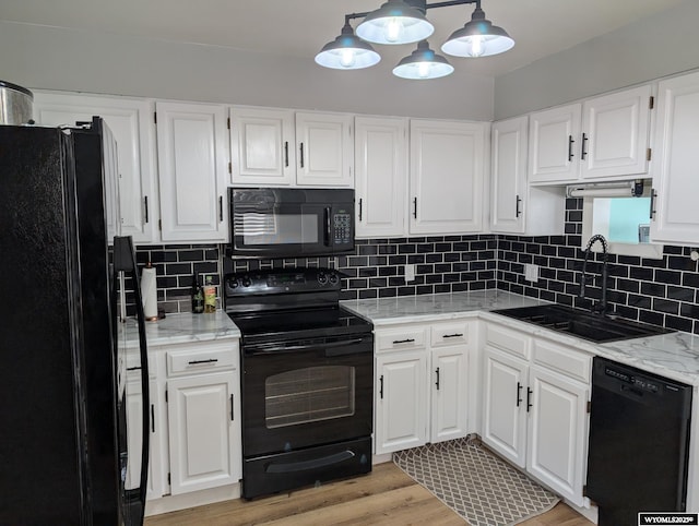 kitchen featuring tasteful backsplash, light wood-style floors, white cabinetry, a sink, and black appliances