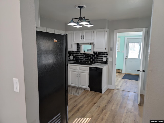 kitchen featuring decorative backsplash, light wood-style flooring, black appliances, white cabinetry, and a sink