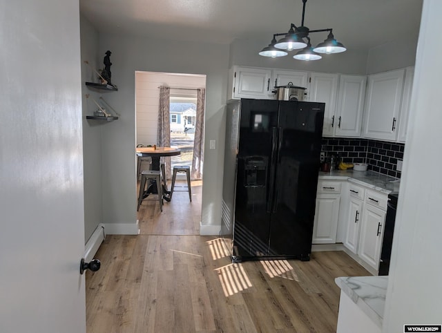 kitchen featuring light wood finished floors, backsplash, black fridge with ice dispenser, and white cabinets