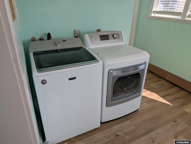 clothes washing area with laundry area, wood finished floors, and washer and dryer