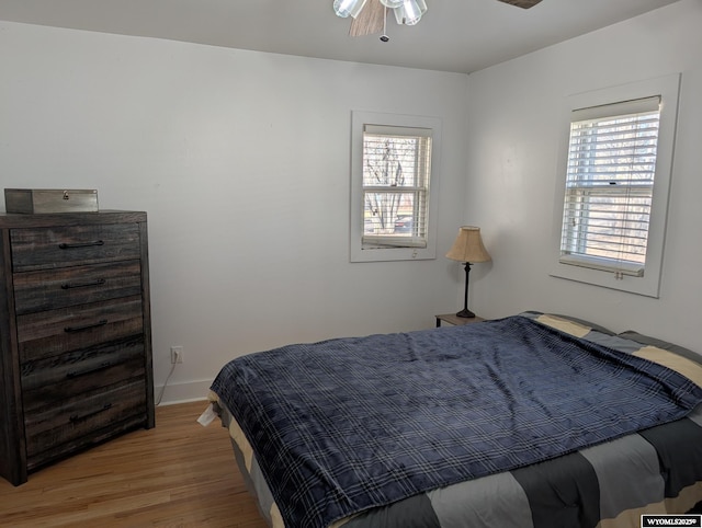 bedroom featuring multiple windows, wood finished floors, and baseboards