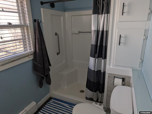 bathroom with a stall shower, a baseboard radiator, toilet, and baseboards