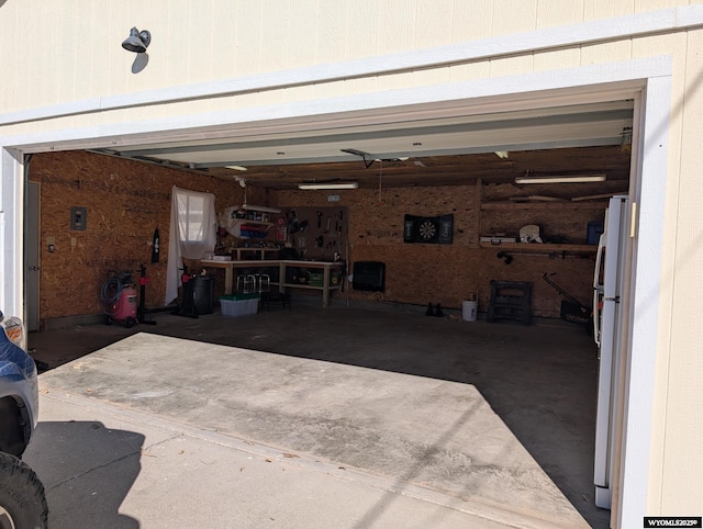 garage featuring a workshop area and freestanding refrigerator