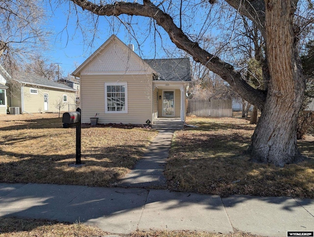 bungalow-style house with a shingled roof, cooling unit, and fence