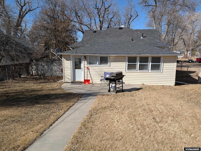 view of front facade featuring a shingled roof, fence, and a patio