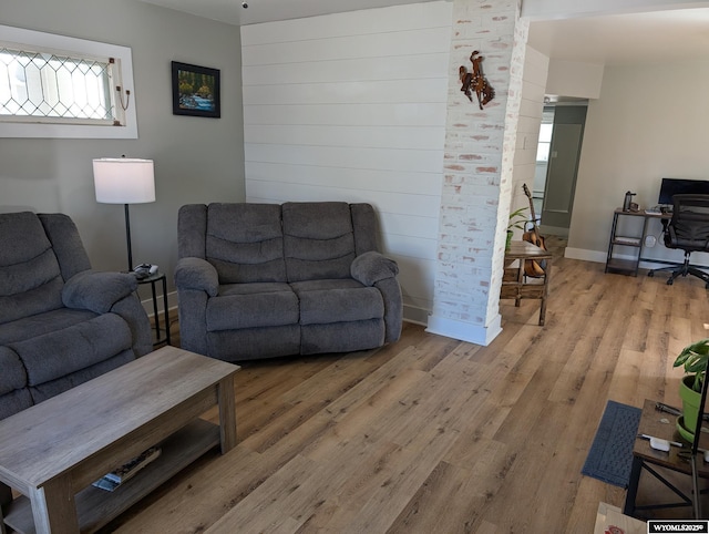 living area with light wood-style floors, baseboards, and wood walls