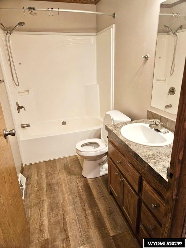 bathroom with visible vents, toilet, wood finished floors, vanity, and shower / washtub combination