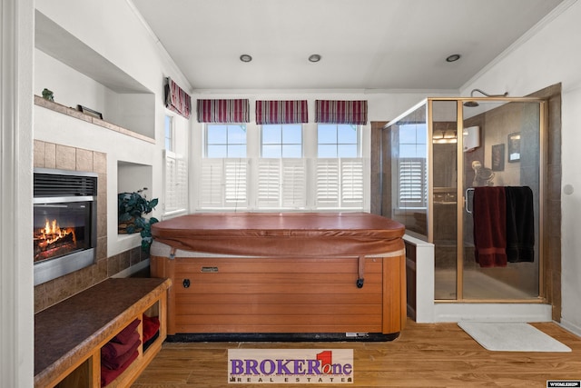 bathroom featuring a shower stall, crown molding, wood finished floors, and a tile fireplace