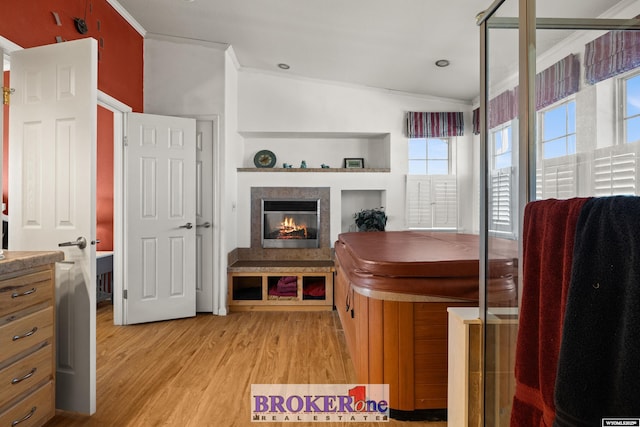 interior space with a tile fireplace, crown molding, and light wood finished floors