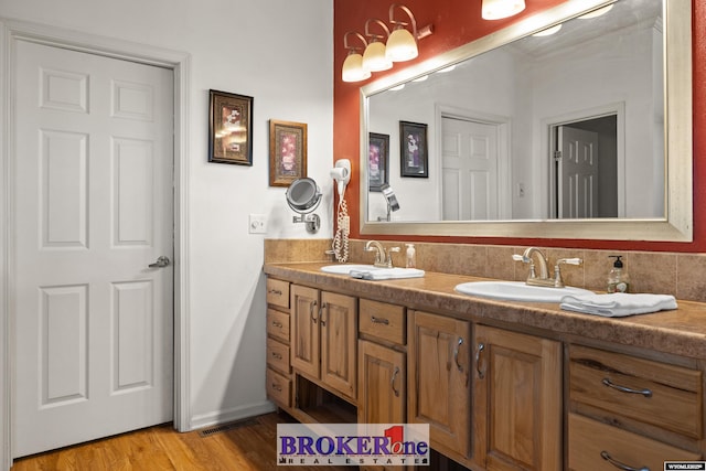 bathroom featuring a sink, visible vents, wood finished floors, and double vanity