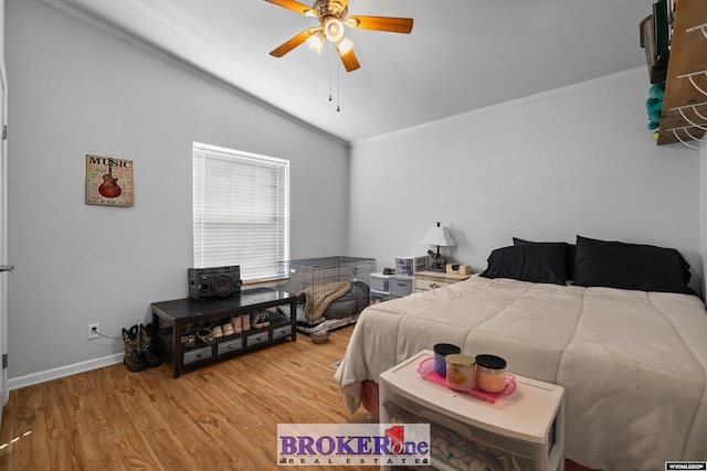 bedroom featuring lofted ceiling, a ceiling fan, wood finished floors, crown molding, and baseboards