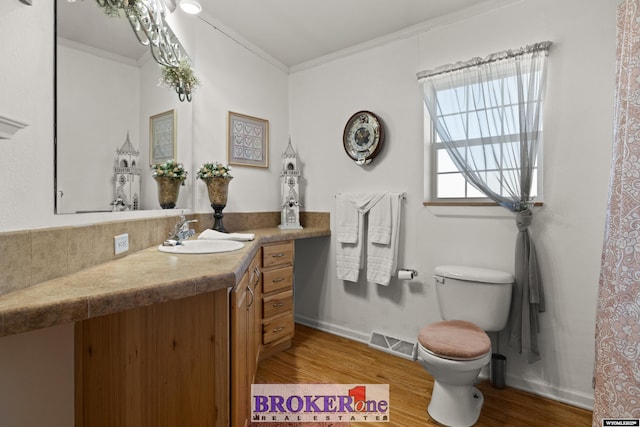 bathroom featuring visible vents, toilet, ornamental molding, wood finished floors, and vanity