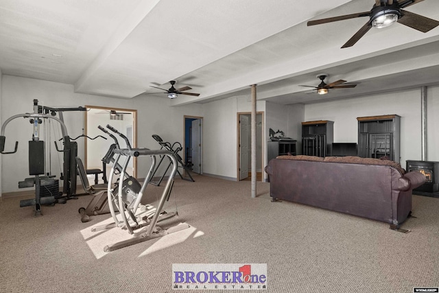 workout room featuring a wood stove, baseboards, and carpet floors