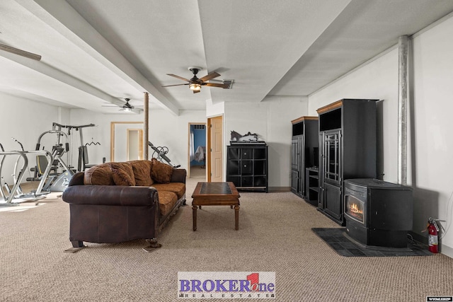 living room featuring beam ceiling, a wood stove, carpet, and ceiling fan