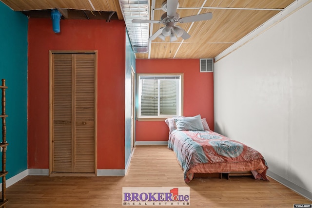 bedroom with a closet, visible vents, baseboards, and wood finished floors